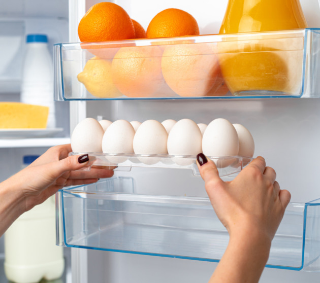 Female hand taking egg from a fridge close up